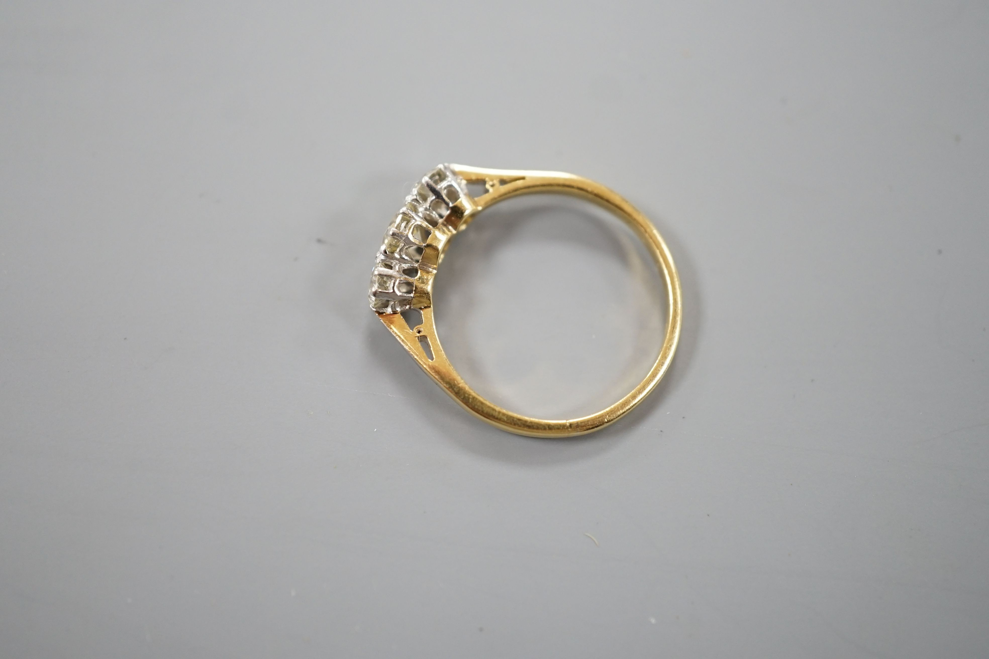 An 18ct gold and platinum three stone diamond ring, size M, gross 2.4 grams.